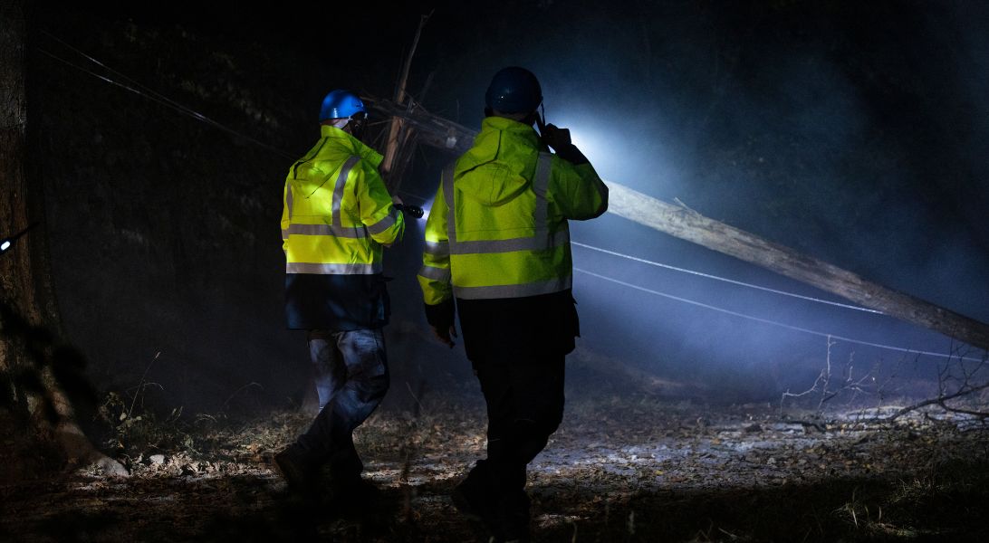 Two ESB Networks staff looking at fallen wires at night