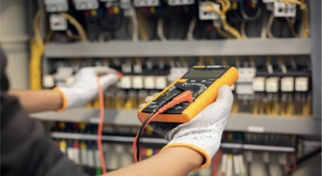 A person holding an electronic multimeter and measuring electrical values.