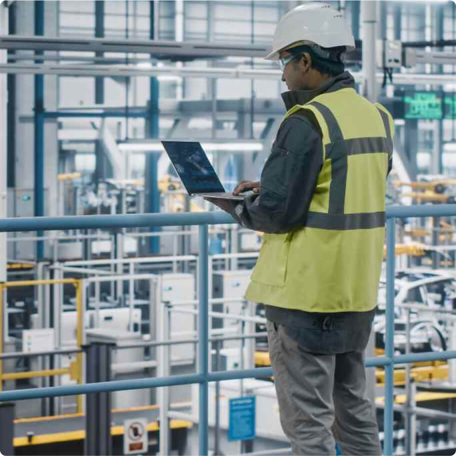 Technician standing with his laptop in a factory