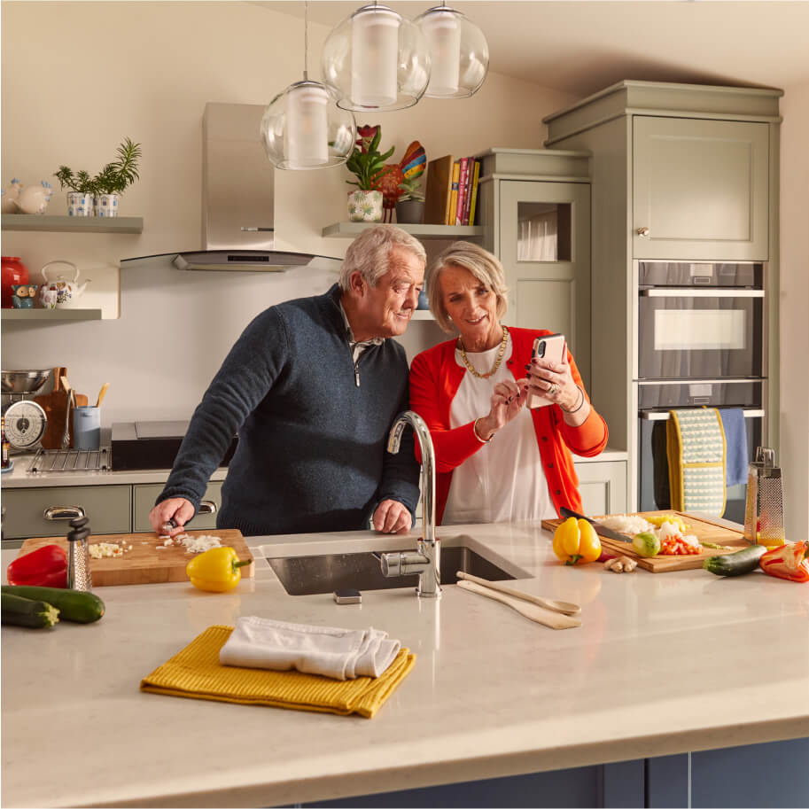Elderly couple looking at phone in the kitchen