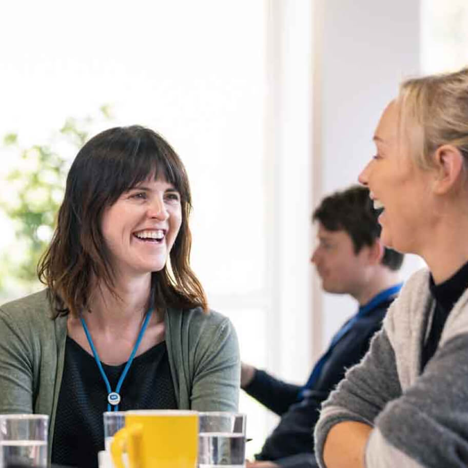 Staff sitting at a table and laughing