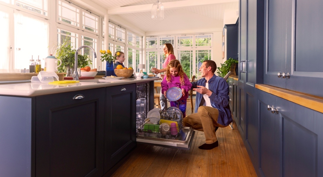 A man and a child loading a dishwasher.
