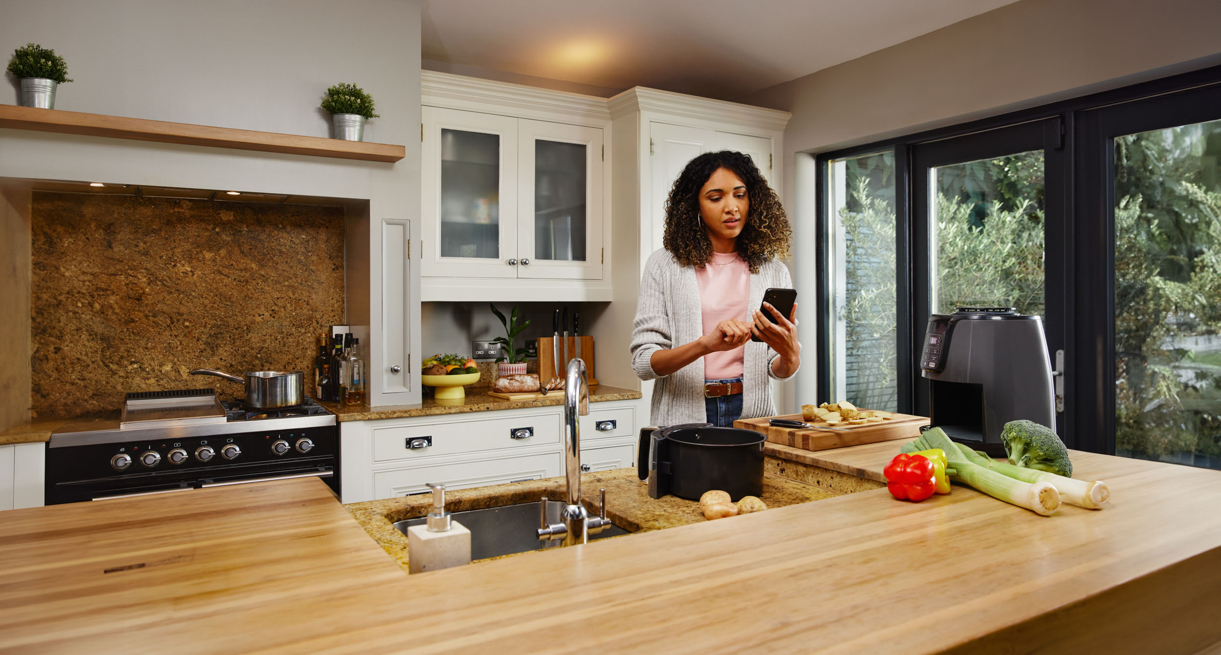A woman using a smartphone in her kitchen.