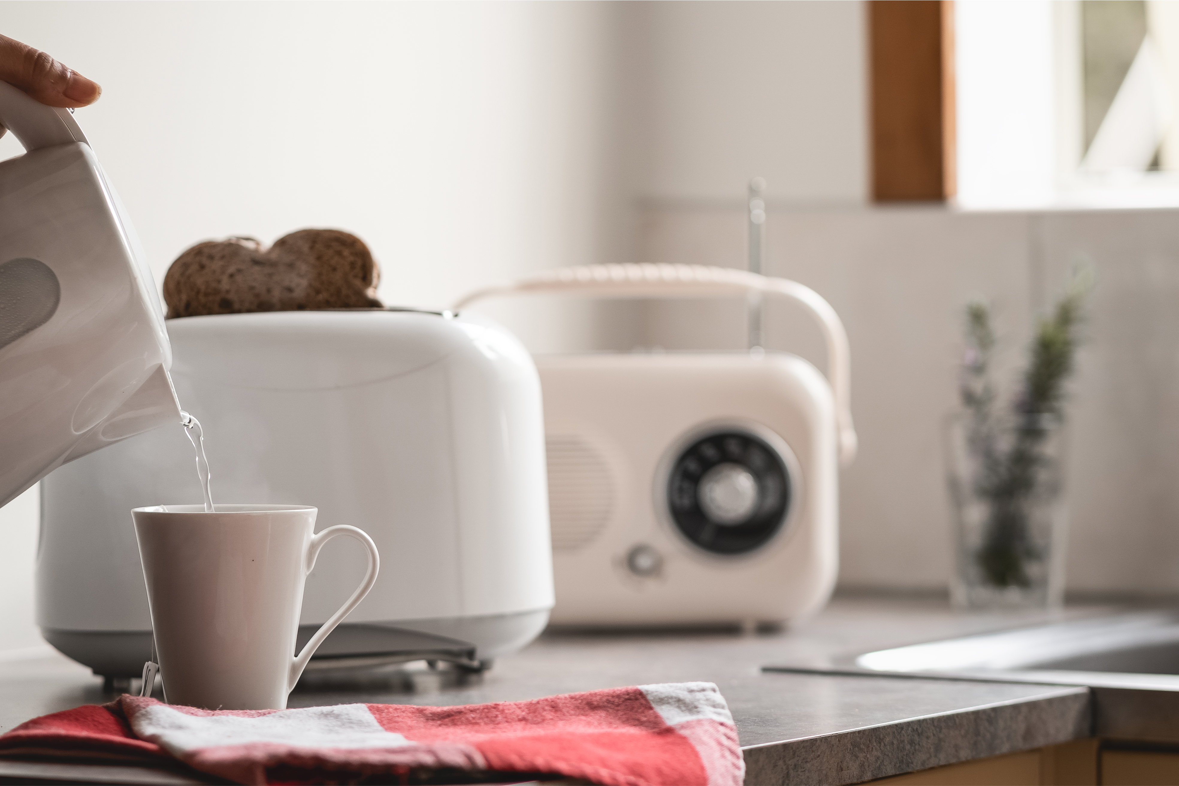 Toaster, radio, kettle and a mug on a kitchen counter.
